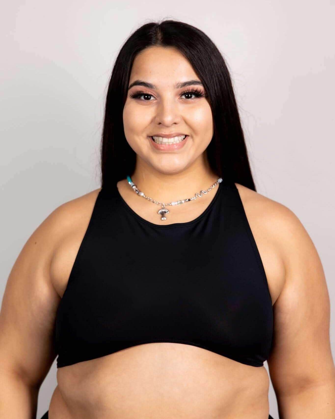 Matte black rave top with high neckline and cutout design modeled against white background front view