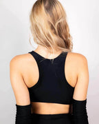 Back view of blonde model wearing matte black teaser rave top with matching arm warmers festival outfit