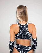 Back view of blonde model wearing black Mechanoid rave top with geometric white patterns and matching festival outfit