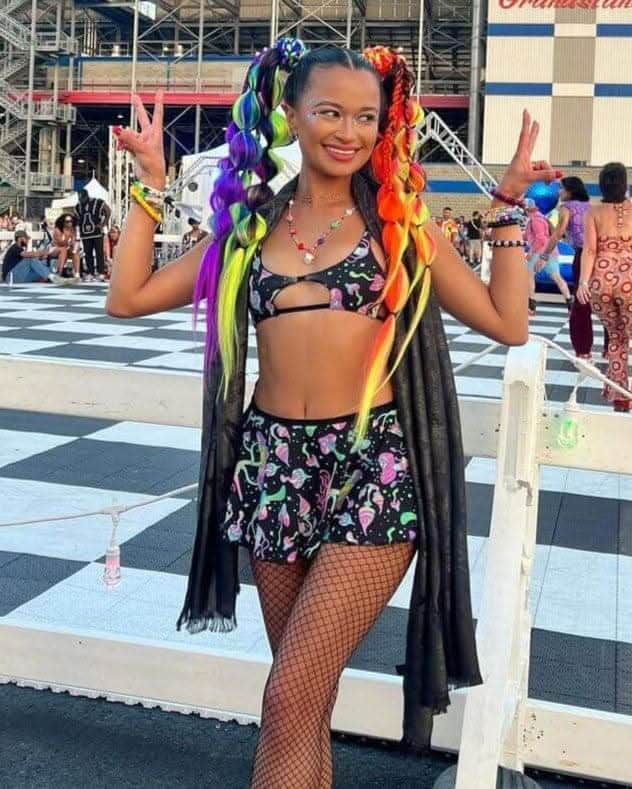 Festival model wearing black Mushies Wonder rave top with colorful mushroom print at outdoor event