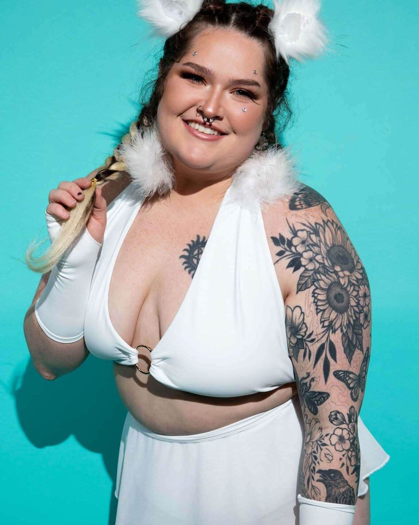 Plus-size model wearing white eco-luxe O-ring rave top with gold hardware and white fur festival accessories front view