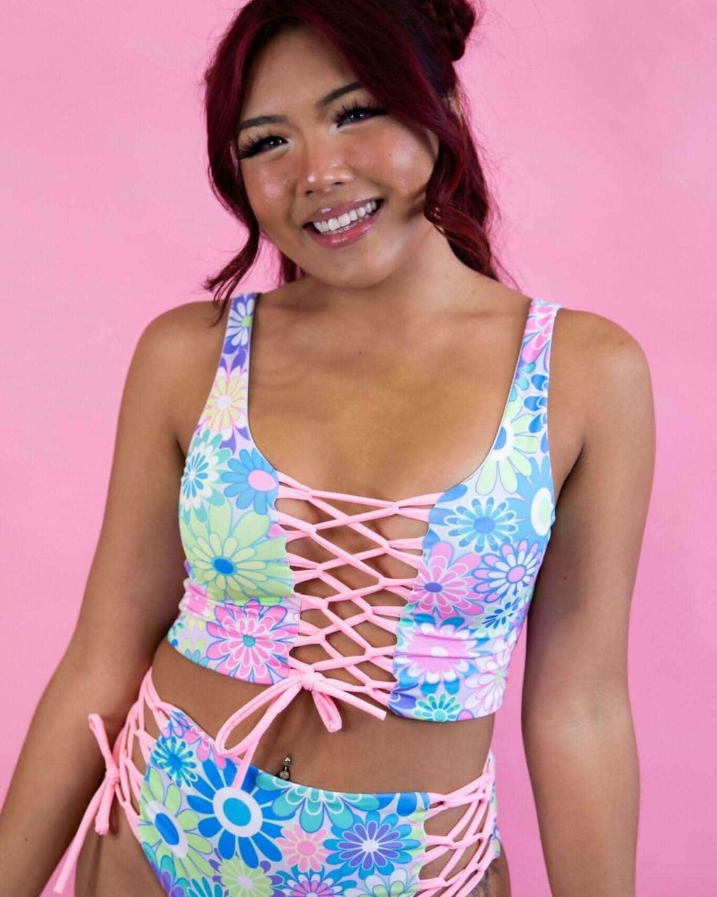 Model in pastel groovy flower print lace-up crop top, showcasing retro vibes and adjustable fit, perfect for rave outfits.