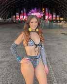 Model in stylish black and white bikini at a festival, showcasing trendy rave outfits and vibrant accessories.
