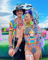 Colorful couple in rave outfits posing by a pool, featuring psychedelic prints and accessories at a vibrant festival event.