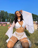 Woman in a white eco-luxe O-ring halter top and flowy sleeves, enjoying summer at a festival, showcasing sustainable rave outfits.