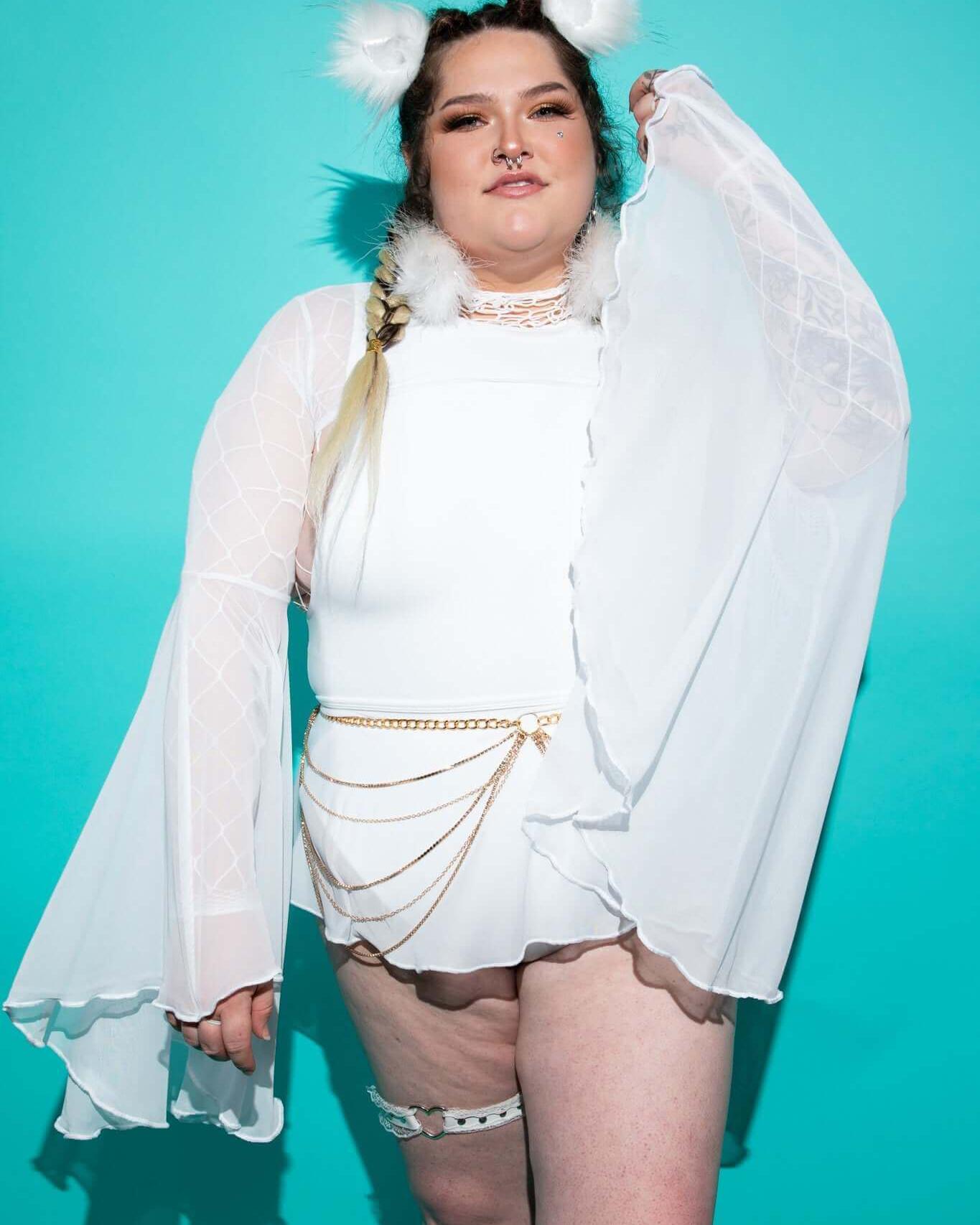 Model showcasing white mesh bell sleeves with dramatic flares, perfect for rave outfits against a vibrant turquoise backdrop.