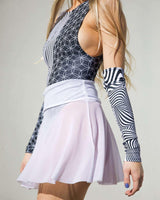 Model wearing a stylish white mesh skater skirt paired with a patterned bodysuit and matching arm sleeves for rave outfits.